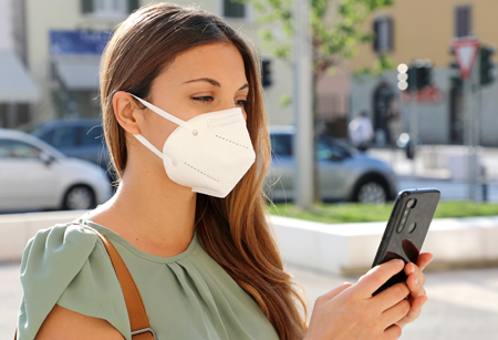 person on their phone with face mask on