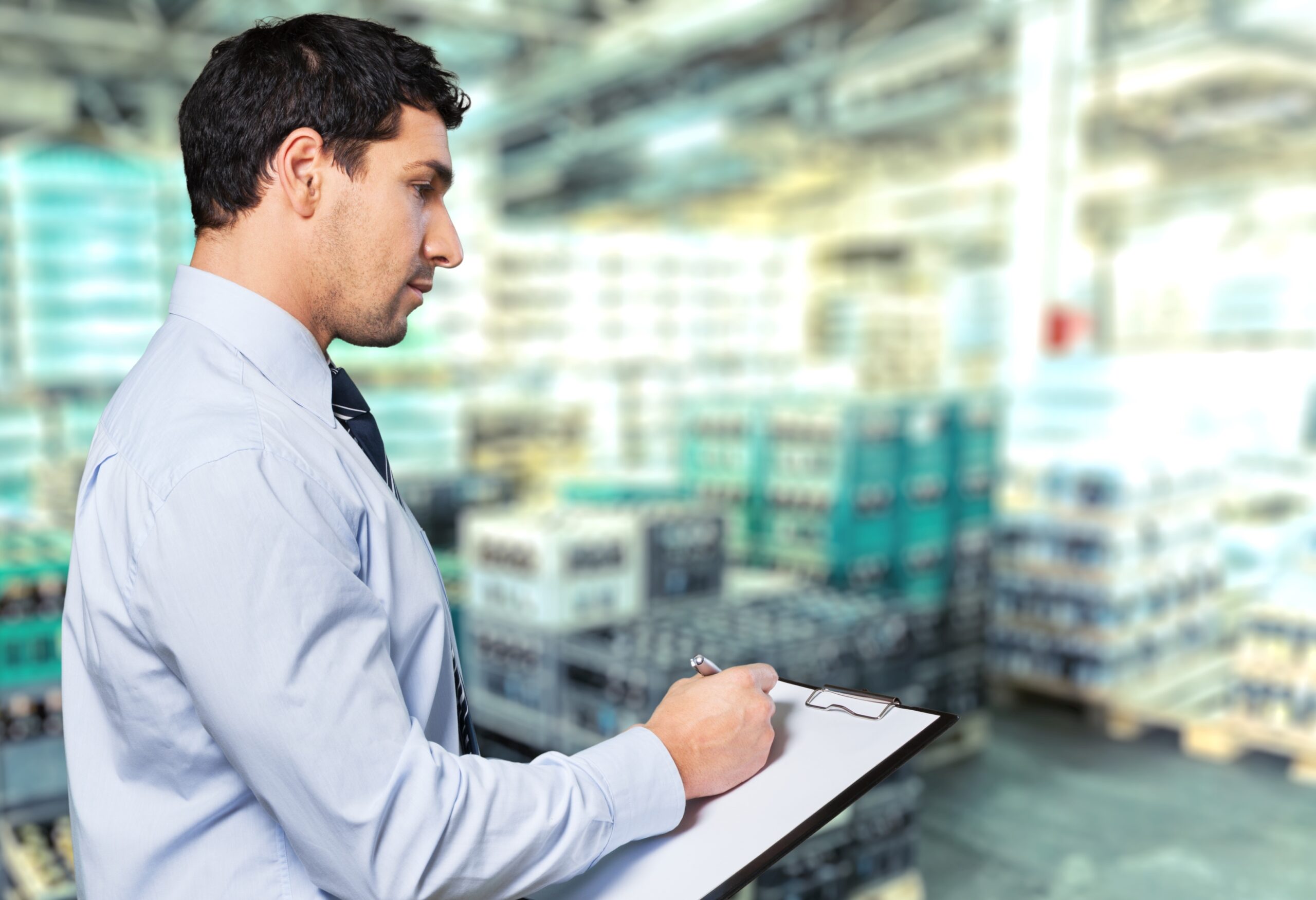 Engineer with a clipboard reviewing Professional standards in a warehouse or factory