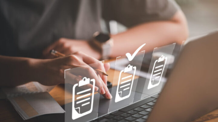 Hand using laptop computer with virtual screen and document for online approve paperless quality assurance and ERP management concept.