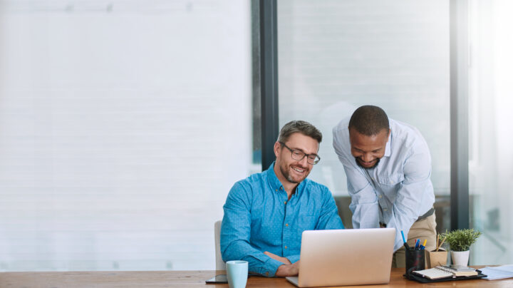 Shot of two businessmen working on a laptop in their office.