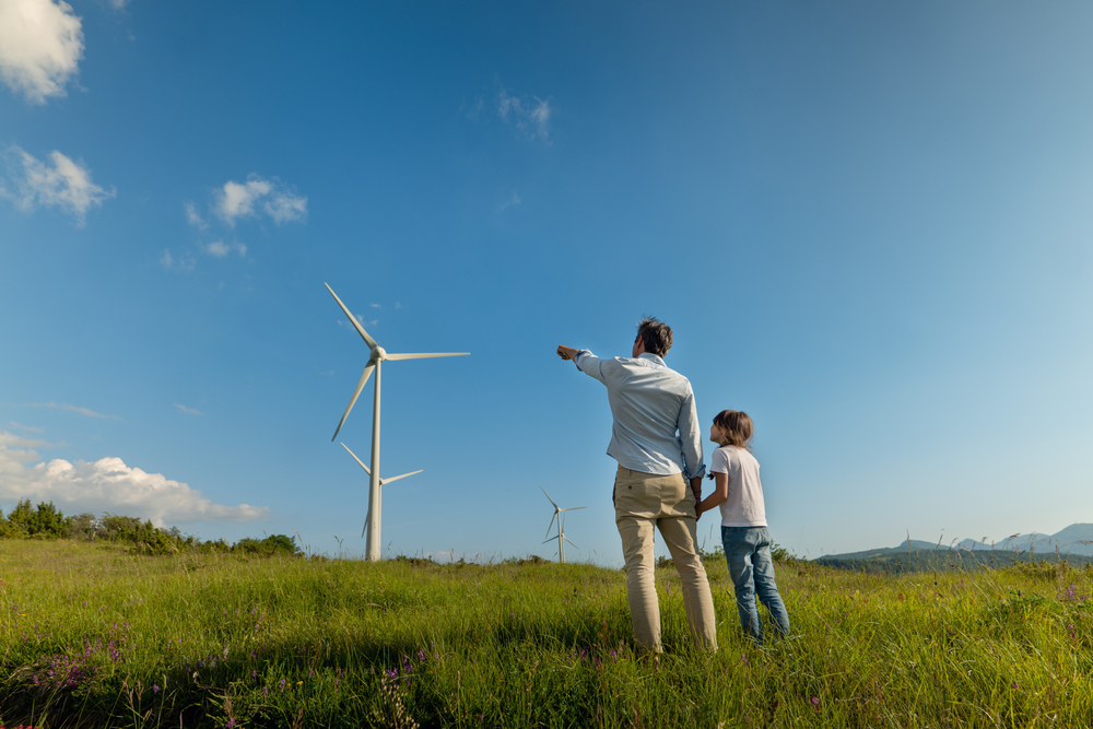 A parent and child looking at a wind turbine on a mountain - a blog about biodiversity legislation