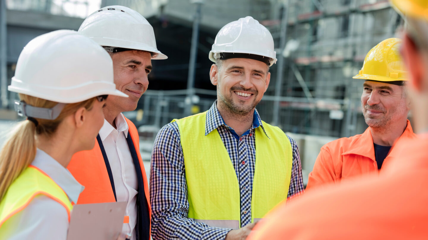 Smiling engineers construction workers meeting at construction site
