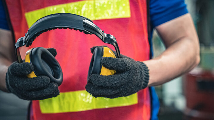 industrial worker holding ear protection gear