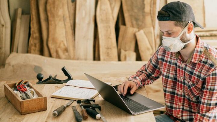 man using a laptop at a wood workshop